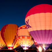 A group of hot air balloons lit up at night.