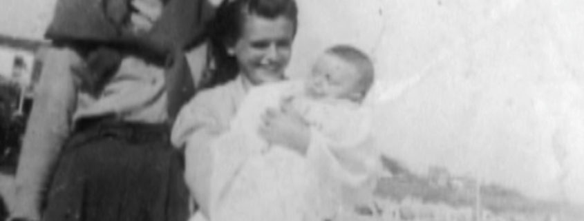 A black and white photo of two men, one holding a baby.